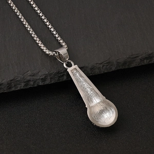 Silver stainless steel microphone pendant necklace on a dark rock background