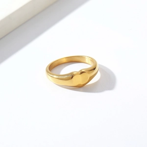 Close-up of a minimalist gold heart signet ring with a polished mirror finish surface