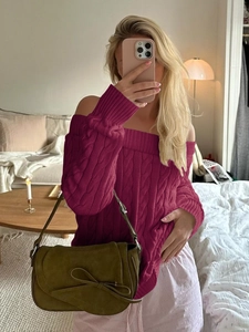 Detail of burgundy off-shoulder cable knit sweater paired with a green suede handbag