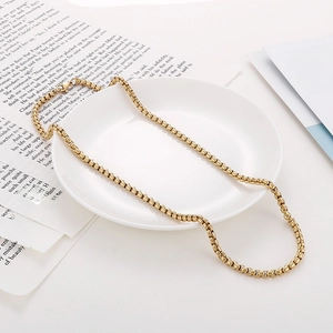 Detailed view of an 18K gold-plated box chain necklace on a ceramic plate