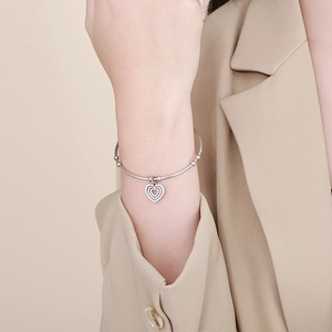 Detailed view of a silver triple layered heart pendant bangle worn with elegant office attire
