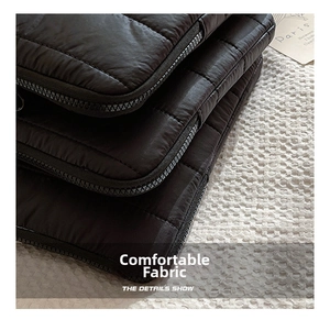 Close-up of black quilted laptop sleeve showing square texture and durable zipper