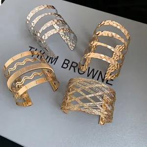 Set of four textured metal cuff bracelets featuring gold and silver wavy hollow designs