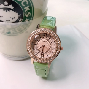 Detail view of a rose gold watch with sparkling diamond bezel and green leather strap
