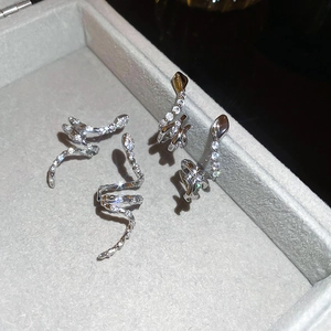 Macro shot of silver snake earrings with pavé cubic zirconia on a gray velvet box