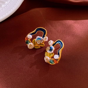 Detailed macro of vintage flower earrings with blue enamel, pearls and crystals on silk