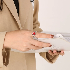 Detailed view of women's silver ring with red heart gemstone and cutout pattern