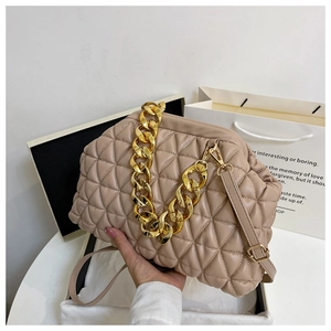 Close-up of quilted beige shell bag with chunky gold chain and leather texture