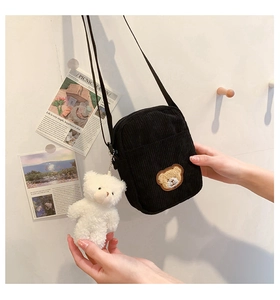 Detail of black corduroy mini crossbody bag with bear patch and plush charm
