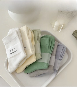 Makro-Detail von gerippten Baumwollsocken in Morandi-Farben mit Papierband-Verpackung