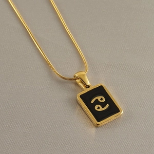 Detailed shot of gold square Cancer zodiac pendant with black enamel on a snake chain