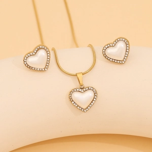 Detail view of gold heart necklace and earrings set with white pearls and crystals