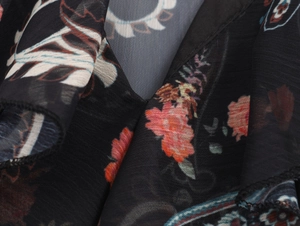 Detailed close-up of semi-transparent black chiffon fabric with red floral prints