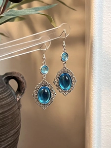 Macro shot of vintage silver earrings with oval blue resin stones on a display stand