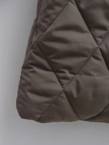 Macro view of brown quilted polyester fabric with diamond pattern and padded details