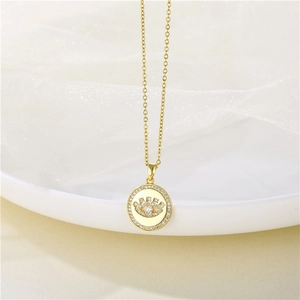 Détail du collier œil protecteur doré avec zircons sur assiette blanche et tissu doux