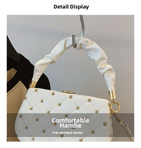 Detail view of the soft ruffled cloud handle and gold floral accents on white handbag