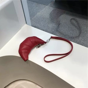 Détail du porte-lunettes en cuir rouge avec fermeture éclair argentée et sangle