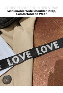 Detail of wide black nylon shoulder strap with white LOVE LOVE text on quilted bag