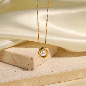 French style gold pearl pendant necklace displayed on a beige stone and silk background