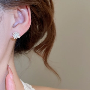 Close-up of elegant silver firework-shaped stud earring worn on model's ear