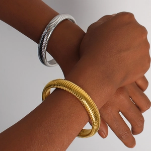 Detalle de brazaletes de malla flexibles en oro de 18K y plata usados en la muñeca