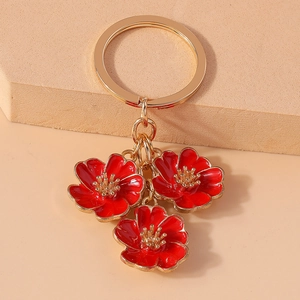 Detailed macro of golden alloy keychain featuring three red enamel peach blossom pendants