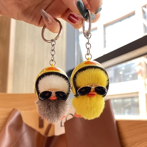 Close-up of yellow and white plush duck keychains with helmets and sunglasses details
