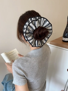 Rear view of striped oversized fabric scrunchie worn on a high ponytail in a home setting