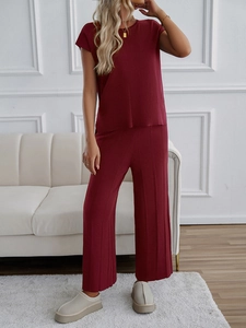 Detail eines weinroten Strick-Sets mit Kurzarm-Oberteil und plissierter Hose mit weitem Bein