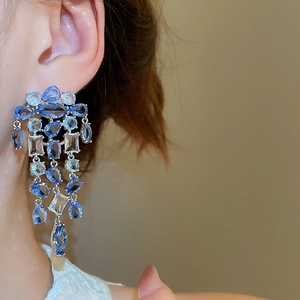 Nahaufnahme eleganter Silberohrringe mit blauen Quadrat- und Tropfenkristallen am Model