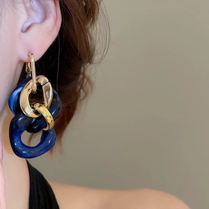 Detail view of large chain earrings with gold metal and blue marble resin rings on a model