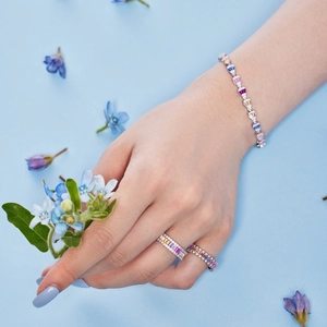 Detail of colorful rectangular zircon ring and bracelet on model with blue flower
