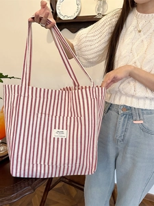 French style red and white striped canvas tote bag worn by a model in a cozy indoor setting
