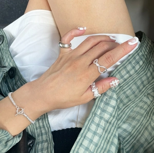 Detail of 925 sterling silver braided twist ring and toggle clasp chain bracelet on hand