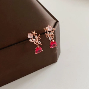 Dettaglio di orecchini a fiore in oro rosa con gemme rosa e rosse a forma di pera