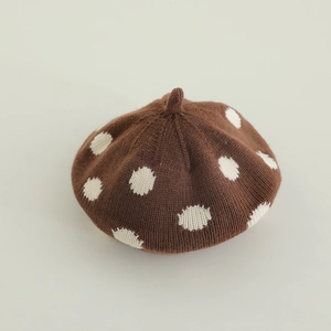 Detail of baby knitted beret featuring brown knit texture and white polka dot pattern