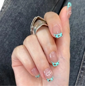 Détail de faux ongles French vert menthe avec motif léopard et nœud blanc