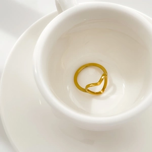 Detail shot of heart hollow geometric gold ring placed on white ceramic base