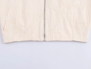 Macro detail of cream floral embroidery texture and silver zipper on the casual jacket