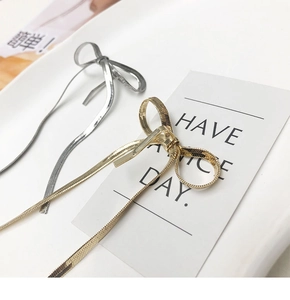 Detailed close-up of metallic bow hair clips with long tassels in gold and silver finishes