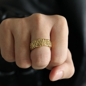 Close-up of golden Viking style triangle geometric ring with textured surface on hand
