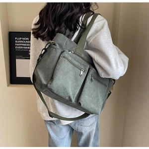 Detailed back view of a green corduroy shoulder bag with multi-pocket texture on model