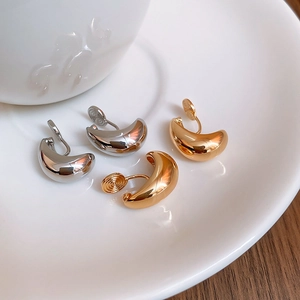 Dettaglio di orecchini a clip a goccia in oro e argento su un vassoio di ceramica