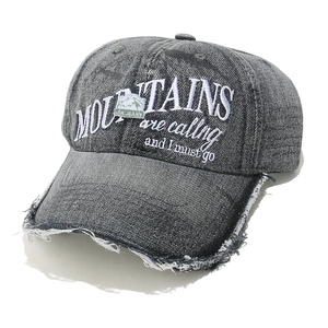 Close-up of distressed charcoal denim cap with mountain embroidery and frayed brim detail