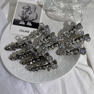 Sparkling bow hair clips with silver and grey rhinestones on a decorative tray