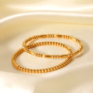18K gold plated stainless steel bead bracelets set on white silk fabric background