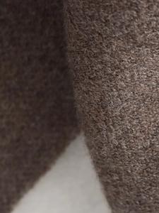 Macro shot of dark brown chunky knit wool fabric texture showing detailed soft plush fibers