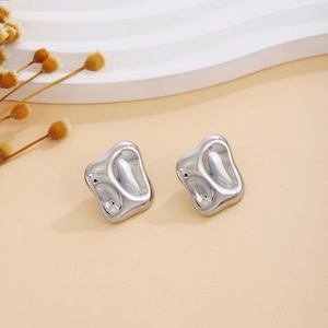Detailed view of silver liquid metal heart earrings on an elegant decorative stand