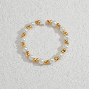 Detail von goldenen Perlen und weißen Perlenarmband mit Sternanhänger auf Textur